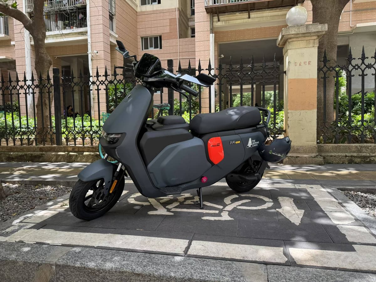 One of Yuzhe's modified electric scooters, parked beside a fence in daylight.